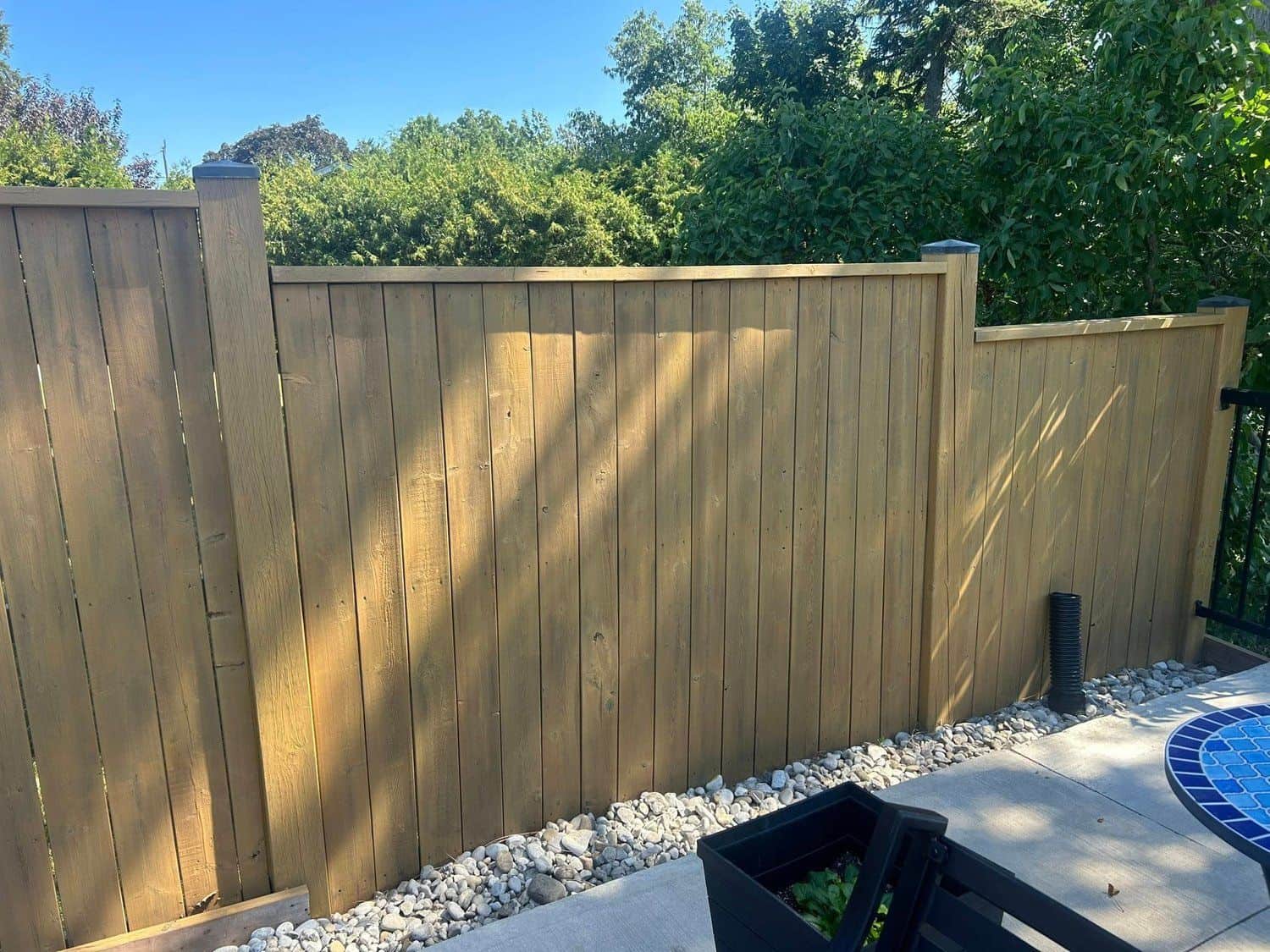 Wood privacy fence with river-rock base by a pool