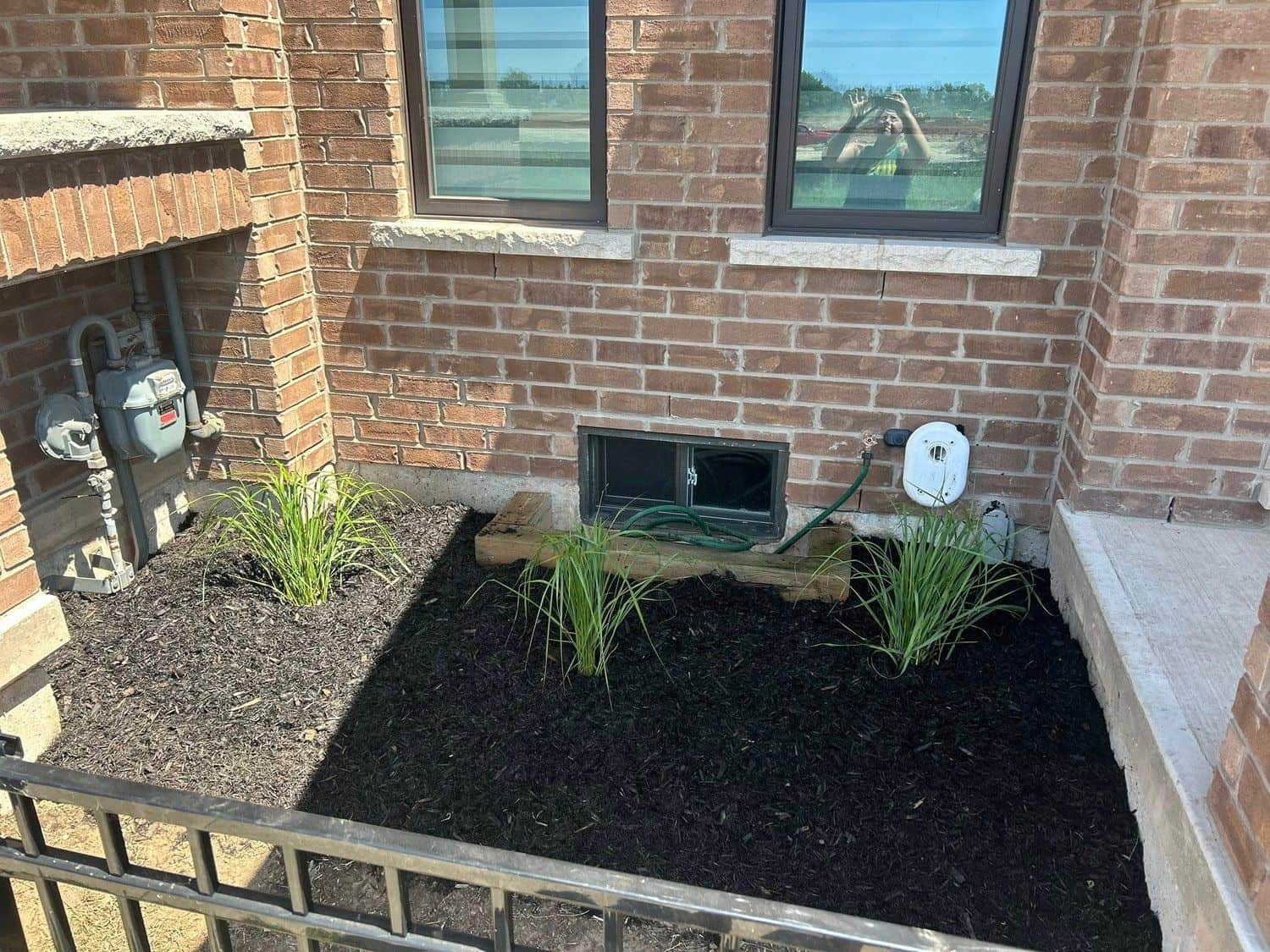 Mulched bed with grasses along a home foundation