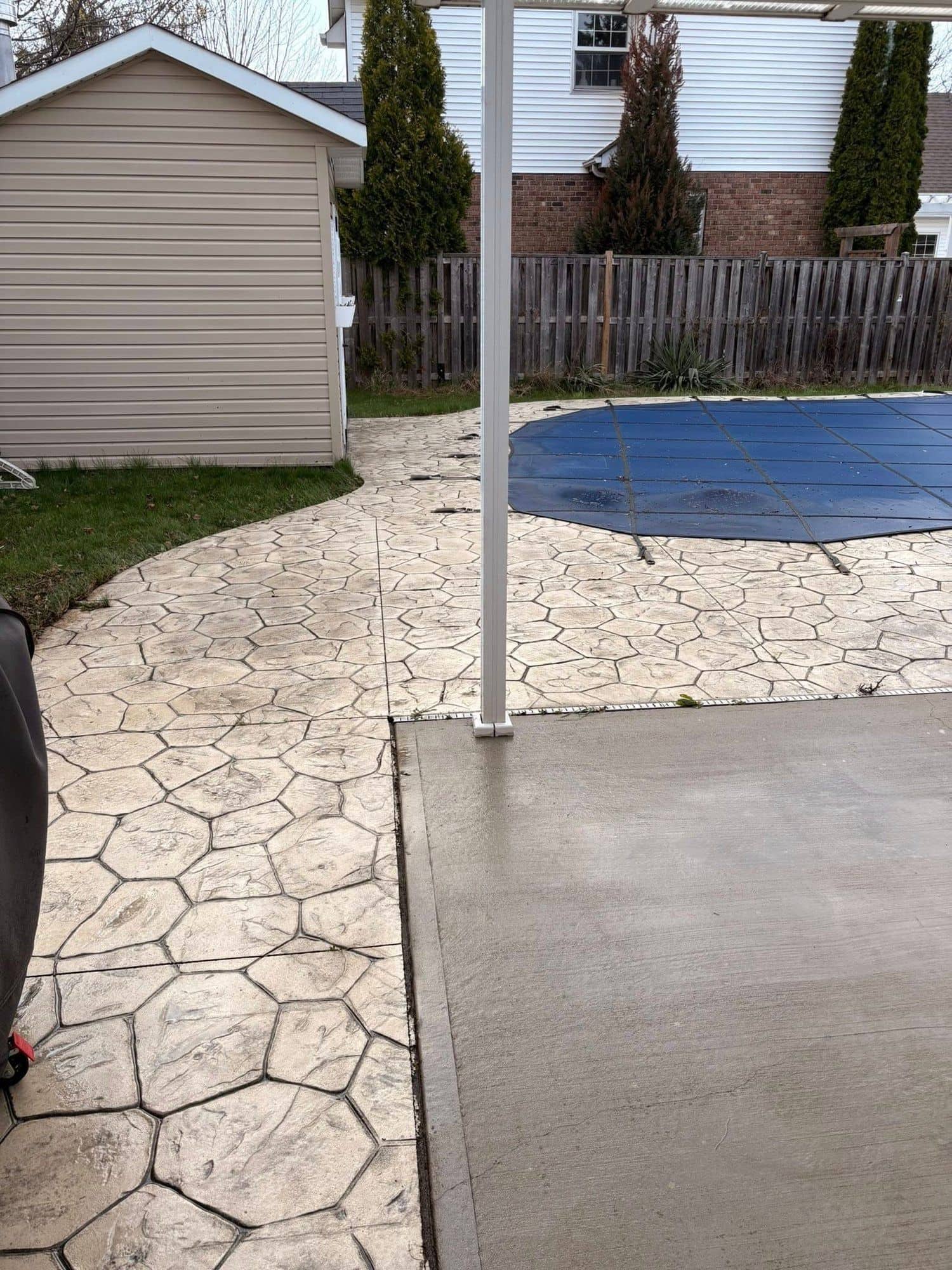 Stamped concrete and interlock walkway beside a backyard pool